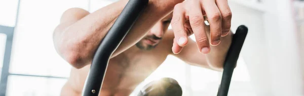 Prise de vue panoramique d'un sportif fatigué s'entraînant sur une machine elliptique au gymnase — Photo de stock