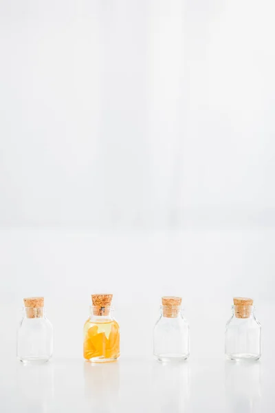 Glass corked bottle with orange essential oil near empty bottles on white background with copy space — Stock Photo