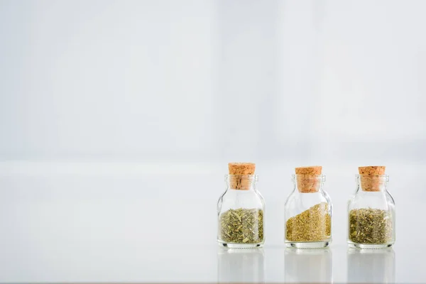 Corked jars with dried herbs on white background with copy space — Stock Photo