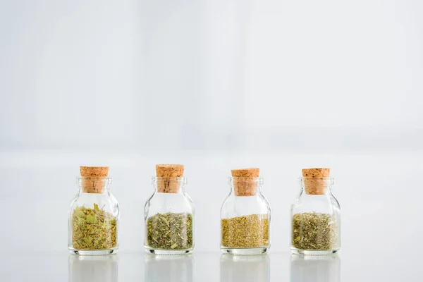 Corked jars with dried herbs on white background with copy space — Stock Photo