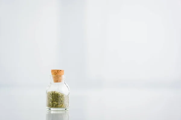 Corked jar with dried herbs on white background with copy space — Stock Photo