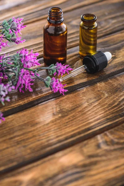 Fiore di erica, bottiglie con olio essenziale e contagocce su superficie di legno — Foto stock