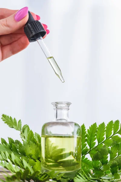 Cropped view of woman holding dropper near bottle with essential oil on white background — Stock Photo