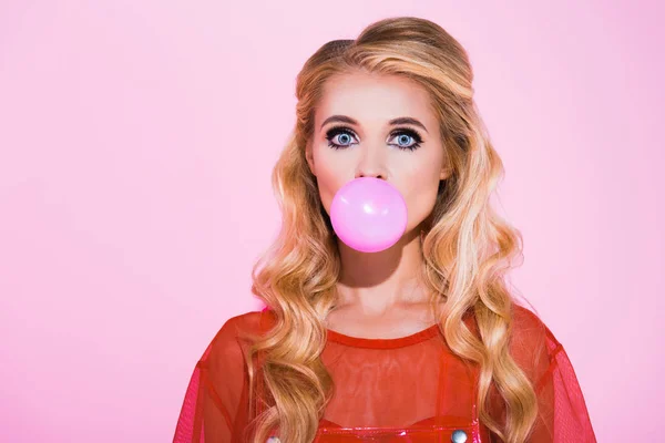 Красивая девушка дует пузырь жевательная резинка изолированы на розовый, кукла концепции — стоковое фото