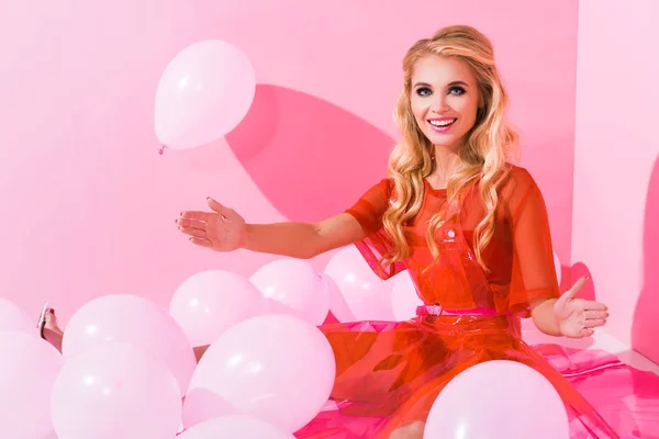 Hermosa chica feliz posando cerca de globos en rosa, concepto de muñeca - foto de stock