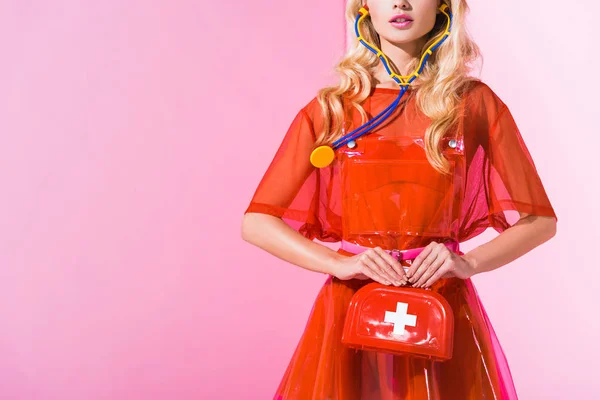 Обрізаний вид дівчини з аптечкою та стетоскопом на рожевому, концепція ляльки — стокове фото