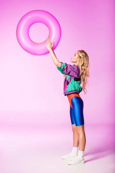 Attractive girl with inflatable swim ring on pink, doll concept — Stock Photo