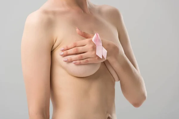 Partial view of topless young woman with pink ribbon covering breast isolated on grey — Stock Photo