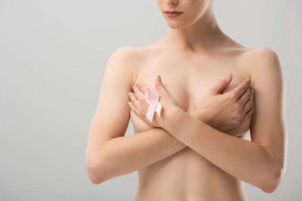 Partial view of topless young woman with pink ribbon covering breast isolated on grey — Stock Photo