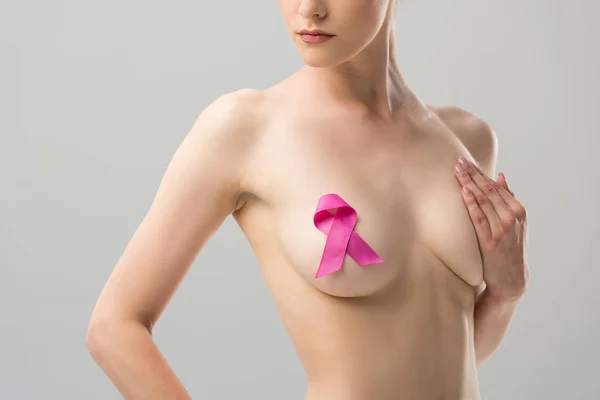 Cropped view of naked young woman with pink ribbon isolated on grey — Stock Photo