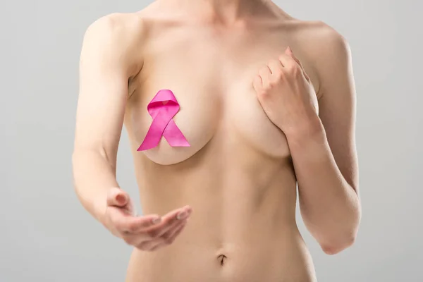 Cropped view of naked young woman with pink ribbon with outstretched hand isolated on grey — Stock Photo