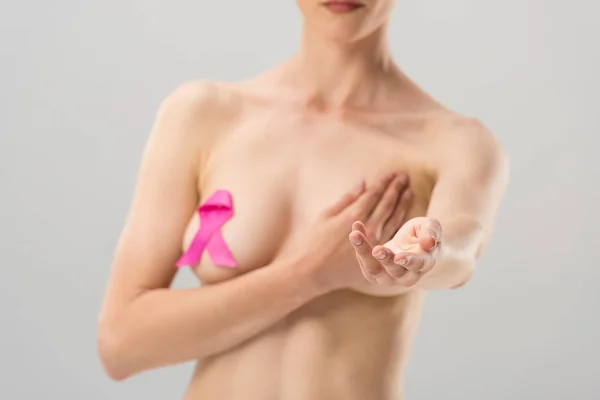 Selektiver Fokus der nackten jungen Frau mit rosa Schleife mit ausgestreckter Hand isoliert auf grau — Stockfoto