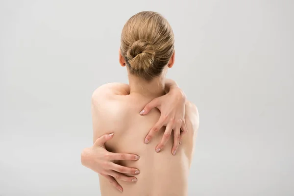 Vista posteriore della donna nuda che si abbraccia isolata sul grigio — Foto stock