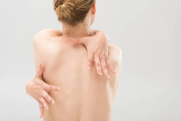 Visão traseira da mulher nua abraçando-se isolado no cinza — Fotografia de Stock