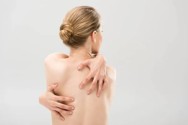 Vista posteriore della donna nuda sexy che si abbraccia isolata sul grigio — Foto stock