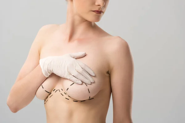 Обрезанный вид женщины в латексной перчатке с отметинами на груди, изолированными на серой — стоковое фото