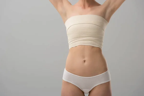 Cropped view of woman with breast bandage with hands up isolated on grey — Stock Photo