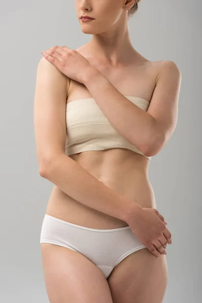 Cropped view of woman in panties with breast bandage isolated on grey — Stock Photo