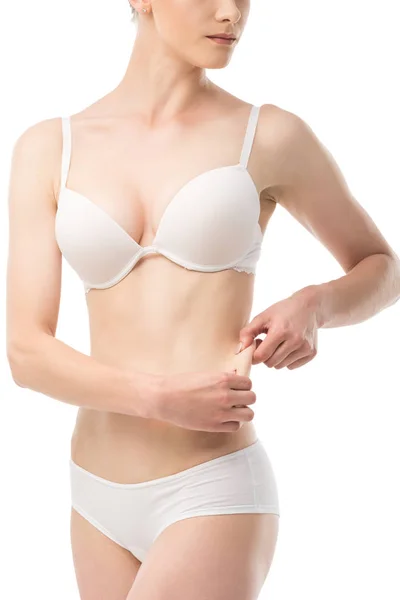 Частковий вигляд молодої жінки в нижній білизні, що показує надлишок ваги ізольовано на білому — стокове фото