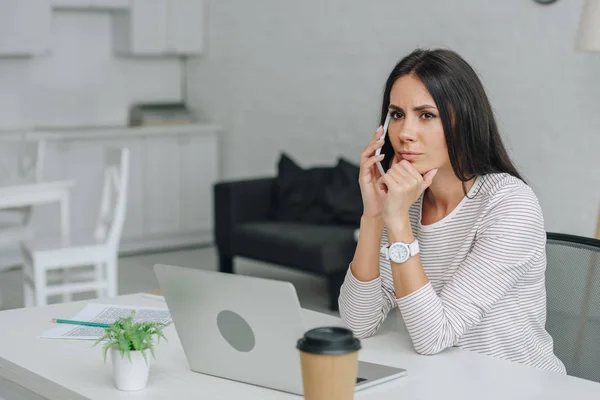 Beautiful and brunette woman talking on smartphone in apartment — Stock Photo