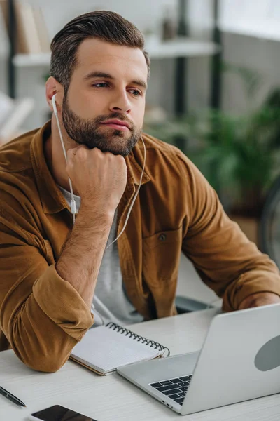 Bel homme en chemise écouter de la musique et détourner les yeux — Photo de stock