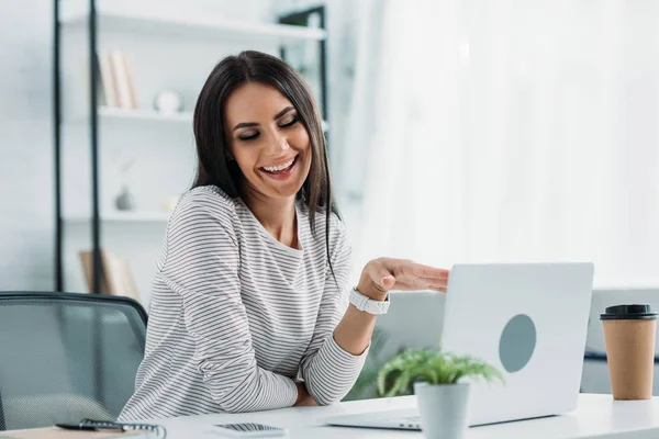 Hermosa y morena mujer con los ojos cerrados sonriendo en apartamento - foto de stock