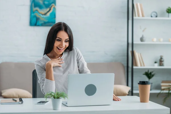 Brunette and attractive woman looking at laptop and smiling — Stock Photo