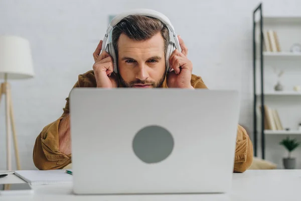 Handsome man listening music and looking at screen of laptop — Stock Photo