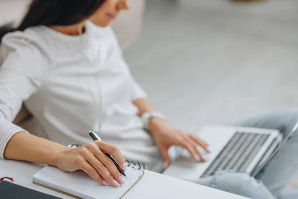 Selective focus of woman using laptop and holding pen — Stock Photo