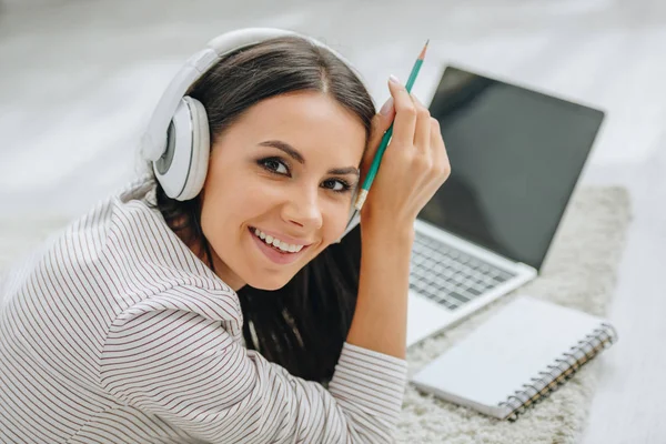 Hermosa mujer con auriculares sonriendo y mirando a la cámara - foto de stock