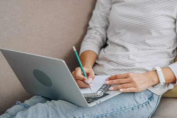 Visão recortada da mulher escrevendo em notebook e segurando laptop — Fotografia de Stock