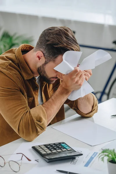 Upset man in shirt holding papers and looking down — Stock Photo