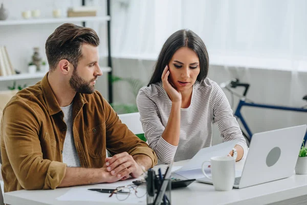 Beautiful and brunette woman looking at paper and talking with handsome man — Stock Photo