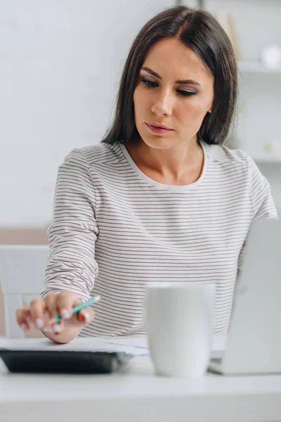 Selektiver Fokus der schönen Frau, die Bleistift in der Hand hält und in der Wohnung rechnet — Stockfoto