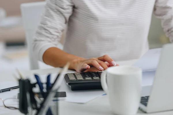 Cropped view of woman in white jersey using calculator in apartment — Stock Photo