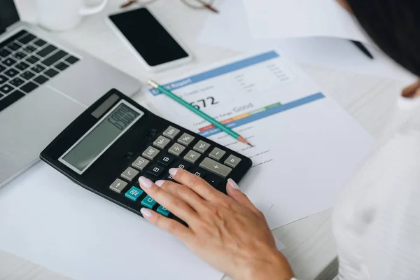 Vista recortada de mujer joven adulta usando calculadora en apartamento - foto de stock