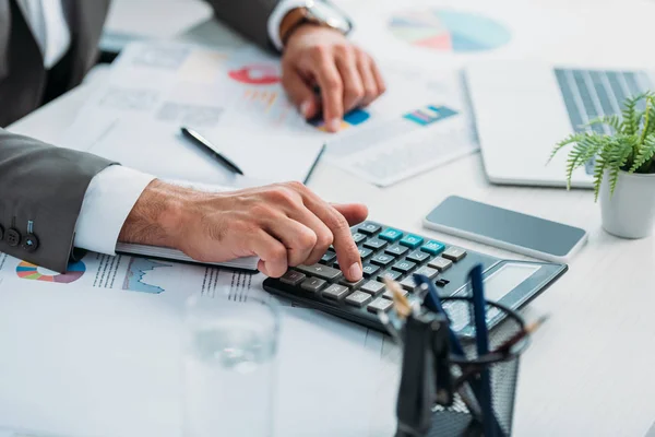 Enfoque selectivo del hombre joven adulto utilizando la calculadora entre los documentos - foto de stock