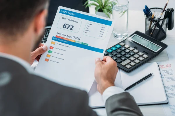 Selective focus of man in formal wear holding credit report — Stock Photo