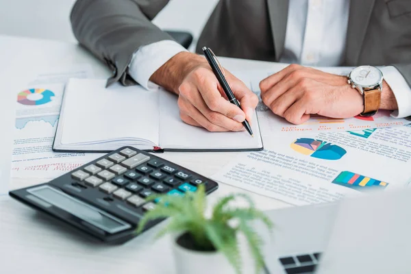 Ausgeschnittene Ansicht eines Mannes, der mit Stift in Notizbuch schreibt — Stockfoto