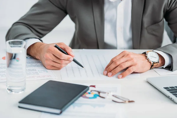 Abgeschnittene Ansicht eines Mannes in formaler Kleidung, der Stift hält und Papierkram erledigt — Stockfoto