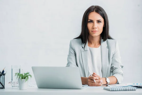 Attractive and brunette woman in formal wear looking at camera — Stock Photo