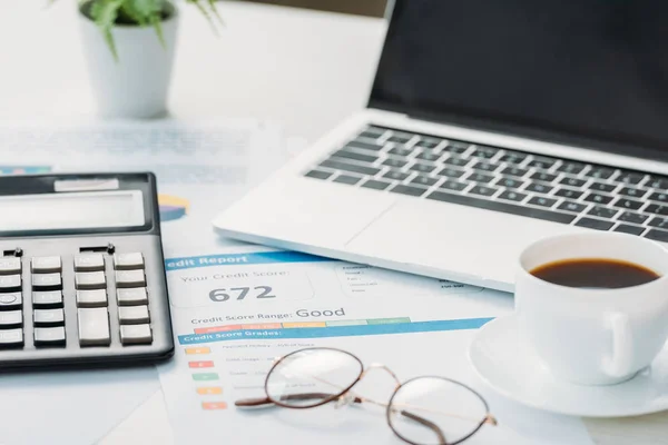 Enfoque selectivo de informe de crédito, calculadora, vasos, taza con café y portátil - foto de stock