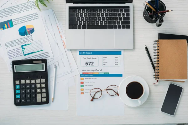 Vue de dessus des lunettes, tasse avec café, rapport de crédit, lunettes, appareils numériques, papeterie et ordinateurs portables — Stock Photo