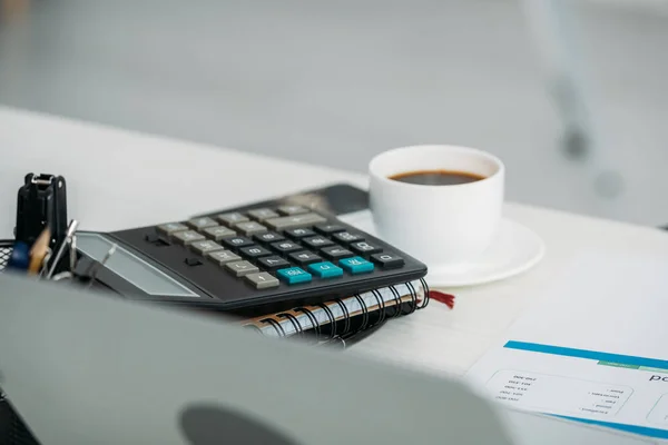 Foco seletivo de xícara com café, calculadora e cadernos — Fotografia de Stock