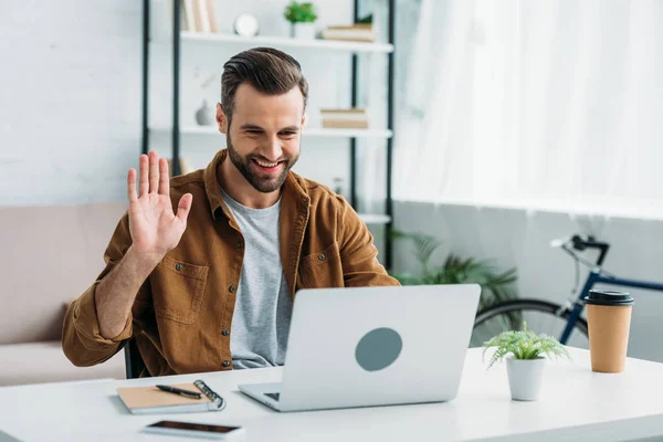 Handsome and happy man smiling and looking at screen of laptop — Stock Photo