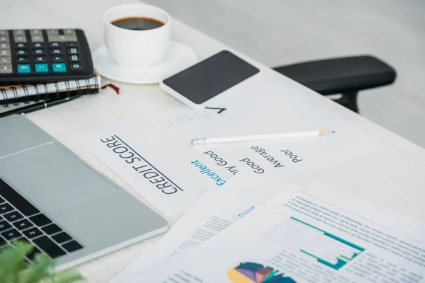 Foyer sélectif du smartphone, tasse avec café, calculatrice, ordinateur portable et pointage de crédit — Photo de stock