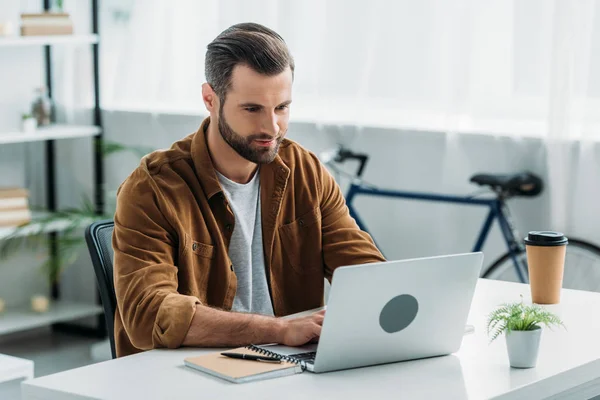 Bello e giovane uomo adulto in camicia utilizzando il computer portatile in appartamento — Foto stock