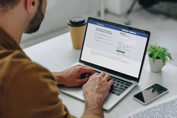 Abgeschnittene Ansicht des Mannes mit Laptop und Facebook-Website auf dem Bildschirm — Stockfoto