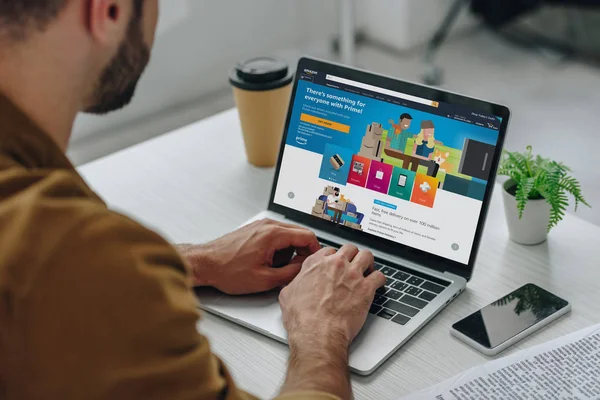 Cropped view of man using laptop with amazon website on screen — Stock Photo