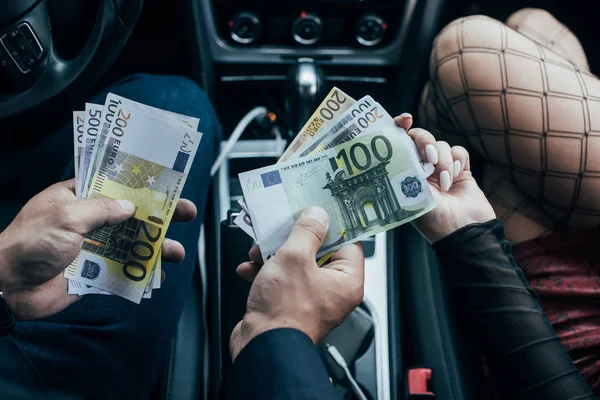 Abgeschnittene Ansicht von Prostituierten in Netzstrümpfen, die Geld von Kunden im Auto erhalten — Stockfoto